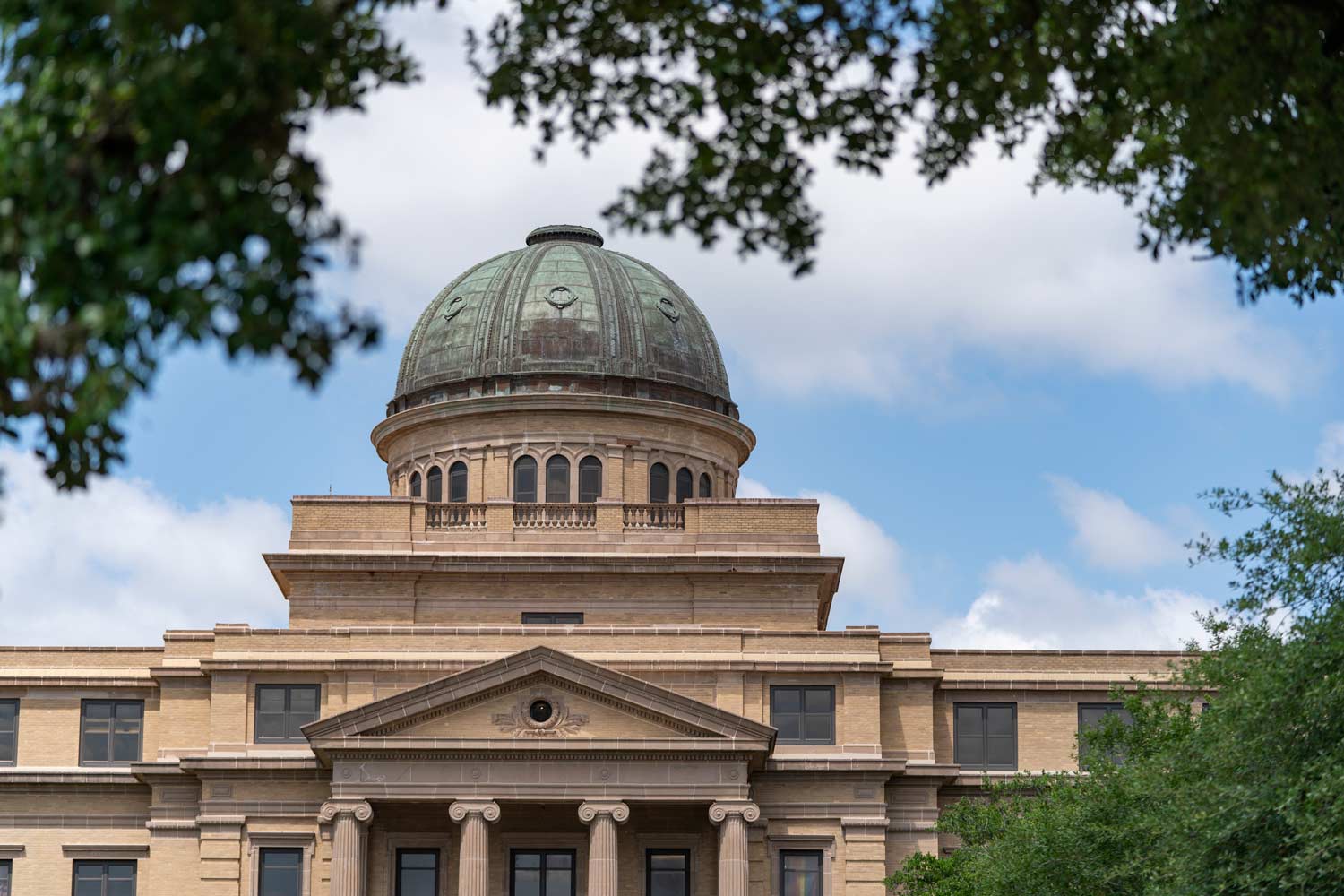 The historic Academic Building dome framed by trees and blue sky