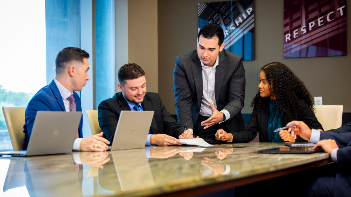 A group at Mays Business School discussing work around a laptop