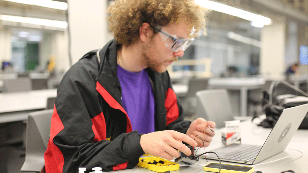 A Texas A&M student working with electronics and a laptop during Invent for the Planet